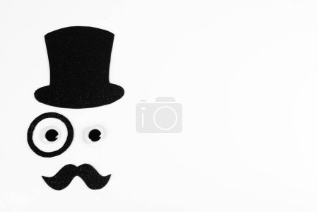 Téléchargez les photos : Visage d'homme fait de fausse moustache, chapeau, yeux et monocle sur fond blanc, vue de dessus. Espace pour le texte - en image libre de droit