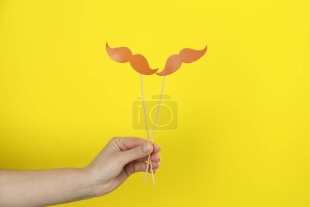 Photo for Woman with fake paper mustaches on yellow background, closeup - Royalty Free Image