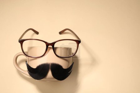 Téléchargez les photos : Moustache artificielle, tasse et verres sur fond beige, vue de dessus. Espace pour le texte - en image libre de droit