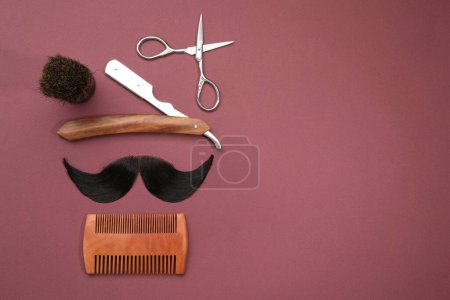 Téléchargez les photos : Moustache artificielle et outils de coiffeur sur fond bordeaux, pose plate. Espace pour le texte - en image libre de droit