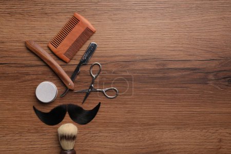 Téléchargez les photos : Moustache artificielle et outils de barbier sur table en bois, pose plate. Espace pour le texte - en image libre de droit