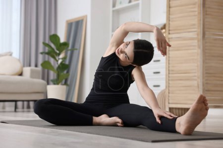 Mädchen, die zu Hause auf einer Yogamatte drehbare Asanas von Kopf bis Knie praktizieren. Parivrtta janu sirsasana pose