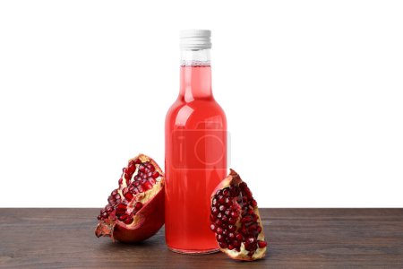 Köstliche Kombucha in Glasflasche und Granatapfel auf Holztisch vor weißem Hintergrund