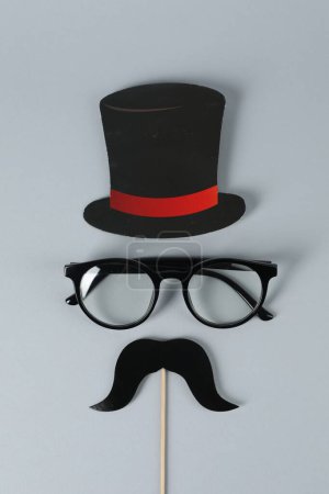 Téléchargez les photos : Fausse moustache avec accessoire de fête, chapeau en papier et lunettes sur fond gris, vue de dessus - en image libre de droit
