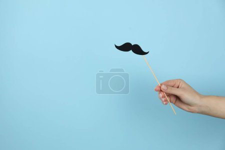 Téléchargez les photos : Femme avec une fausse moustache en papier sur fond bleu clair, gros plan. Espace pour le texte - en image libre de droit