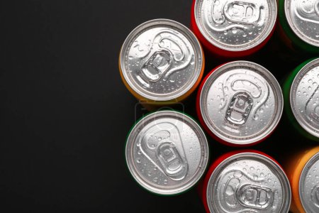 Energy drinks in wet cans on dark background, top view. Space for text