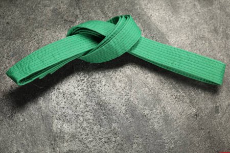 Photo for Green karate belt on gray textured background, top view. Space for text - Royalty Free Image