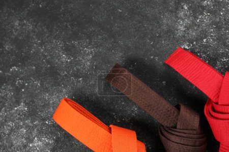 Cinturones de karate de colores sobre fondo gris, planas. Espacio para texto