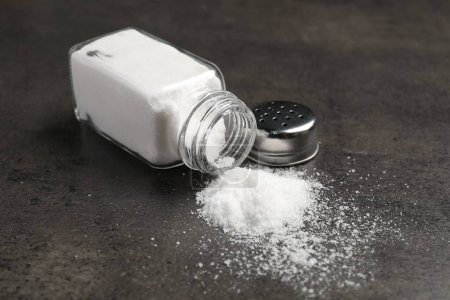 Umgekippter Shaker mit Salz auf grauem Tisch
