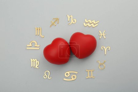 Zodiac signs and red hearts on grey background, flat lay