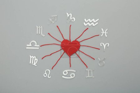 Foto de Compatibilidad con el zodiaco. Signos, corazón rojo e hilos sobre fondo gris, posición plana - Imagen libre de derechos