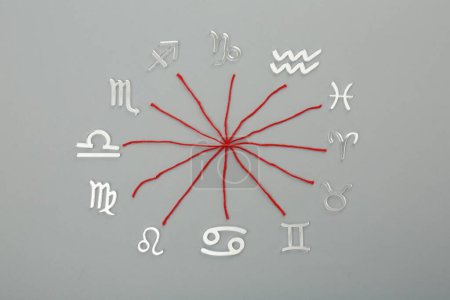Foto de Compatibilidad con el zodiaco. Signos e hilos rojos sobre fondo gris, plano - Imagen libre de derechos