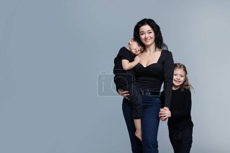 Kleine Kinder mit ihrer Mutter auf grauem Hintergrund. Raum für Text