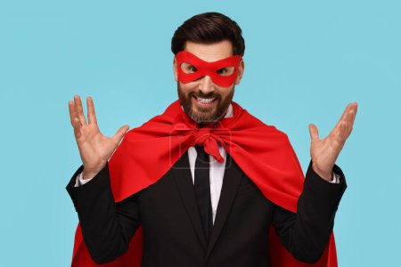 Foto de Hombre de negocios con capa de superhéroe rojo y máscara sobre fondo azul claro - Imagen libre de derechos