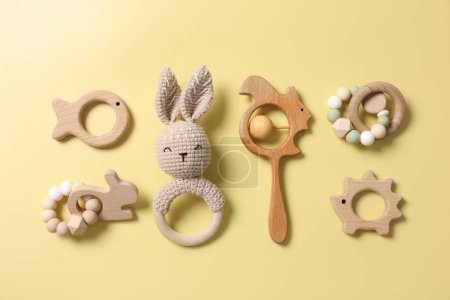Baby accessories. Rattles and teethers on yellow background, flat lay
