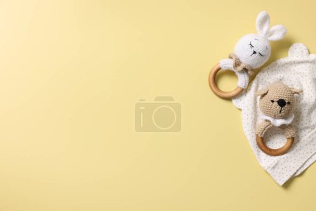 Baby accessory. Rattles and hat on yellow background, top view. Space for text