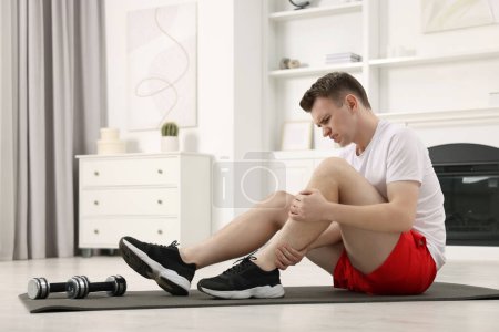 Photo for Man suffering from leg pain on mat at home - Royalty Free Image