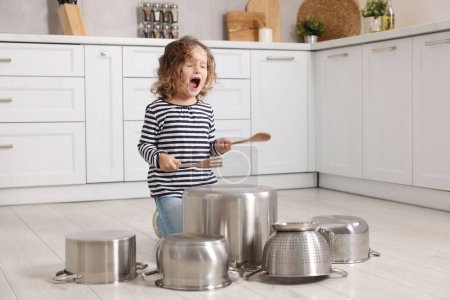 Foto de Niña fingiendo tocar la batería en ollas en la cocina - Imagen libre de derechos