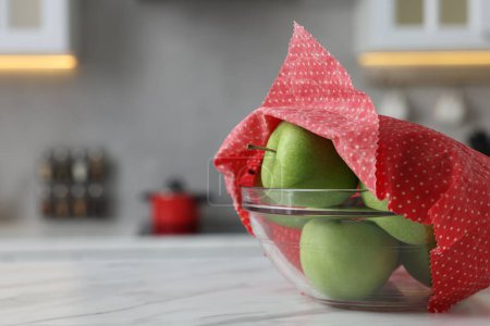 Äpfel in Schale mit Bienenwachsfolie auf weißem Tisch, Nahaufnahme. Raum für Text