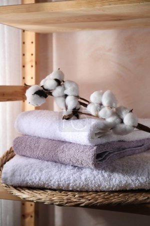 Stapelbare weiche Handtücher und Baumwollzweige im Regal drinnen