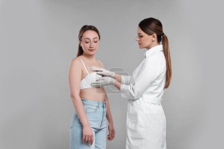Mammologue vérifiant le sein de la femme sur fond gris