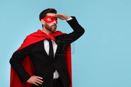 Foto de Hombre de negocios con capa de superhéroe rojo y máscara sobre fondo azul claro. Espacio para texto - Imagen libre de derechos