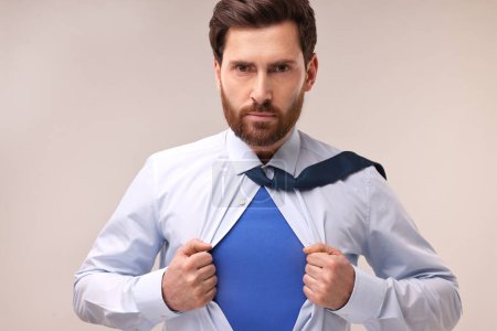 Foto de Hombre de negocios confiado que usa traje de superhéroe bajo traje sobre fondo beige - Imagen libre de derechos