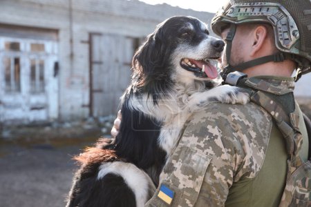 Ukrainischer Soldat rettet streunenden Hund im Freien, Rückansicht. Raum für Text