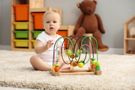Kinderspielzeug. Niedlicher kleiner Junge spielt mit Perlen-Labyrinth auf Teppich zu Hause
