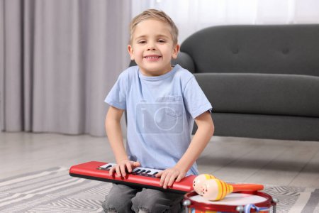 Kleiner Junge spielt zu Hause Spielzeugklavier