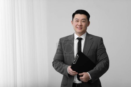 Photo for Portrait of happy notary with clipboard indoors, space for text - Royalty Free Image
