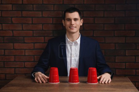 Man playing shell game at wooden table