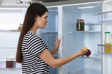 Mujer molesta sacando limón del refrigerador vacío