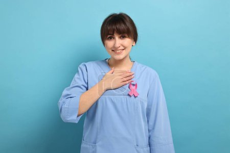 Mammologue avec ruban rose sur fond bleu clair. Sensibilisation au cancer du sein