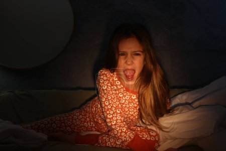 Photo for Childhood phobia. Little girl screaming on bed at home - Royalty Free Image