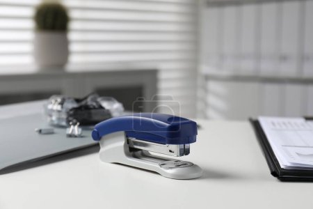 Stapler on white table indoors, closeup view