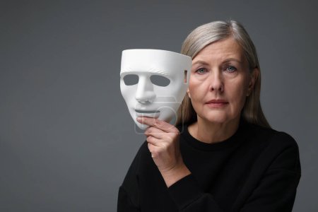 Multiples Persönlichkeitskonzept. Frau mit Maske auf grauem Hintergrund, Platz für Text