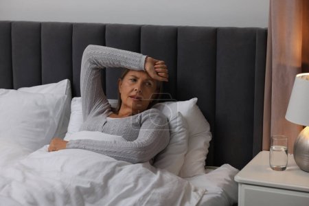 Wechseljahre. Frau leidet unter Kopfschmerzen im Bett