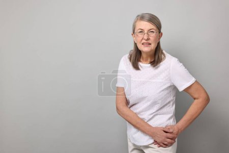 Photo for Arthritis symptoms. Woman suffering from hip joint pain on gray background, space for text - Royalty Free Image