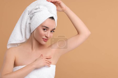 Belle femme montrant aisselle avec une peau lisse et propre sur fond beige