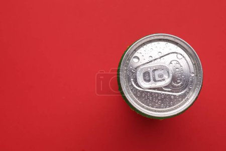 Bebida energética en lata húmeda sobre fondo rojo, vista superior. Espacio para texto