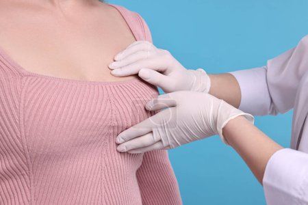 Mammologue vérifiant le sein de la femme sur fond bleu clair, gros plan