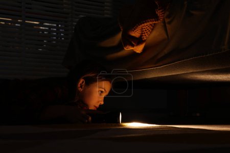 Photo for Little girl with flashlight looking for monster under bed at night - Royalty Free Image