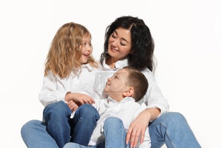 Niños pequeños con su madre sentados juntos sobre fondo blanco