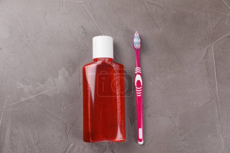 Foto de Enjuague bucal fresco en botella y cepillo de dientes en mesa texturizada gris, vista superior - Imagen libre de derechos