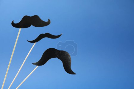 Téléchargez les photos : Faux papier moustaches sur bâtons sur fond bleu. Espace pour le texte - en image libre de droit