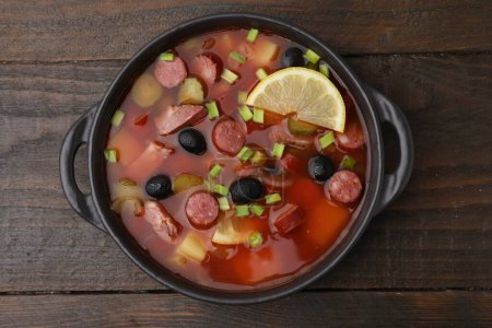 Téléchargez les photos : Soupe de viande solyanka avec de fines saucisses fumées sèches dans un bol sur une table en bois, vue sur le dessus - en image libre de droit