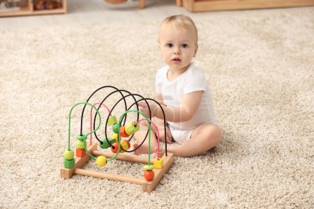 Des jouets pour enfants. mignon petit garçon jouer avec perle labyrinthe sur tapis à la maison