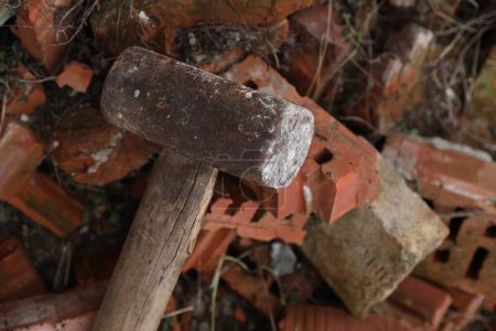 Sledgehammer on pile of broken bricks outdoors, above view