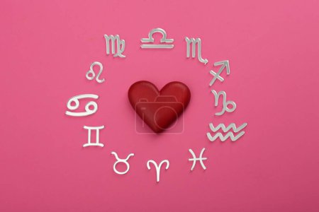 Zodiac signs and red heart on pink background, flat lay